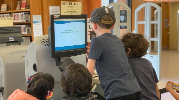 Kids at the self check-out at the Presidio Branch of the San Francisco Public Library.